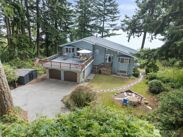 10125 Totem Way, Anderson Island, WA 98303 - view of front of property featuring concrete driveway, a storage shed, an attached garage, and a wooden deck