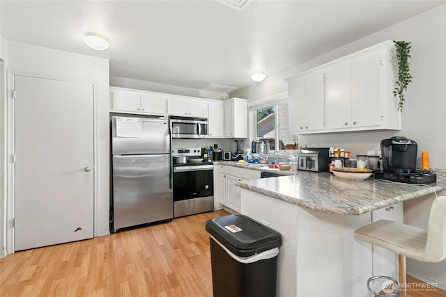 10421 19th Ave SE, Everett, WA 98208 - kitchen featuring stainless steel appliances, a peninsula, white cabinets, and light wood-type flooring