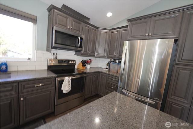 24523 L Ln, Ocean Park, WA 98640 - kitchen featuring stainless steel appliances, lofted ceiling, dark stone countertops, backsplash, and dark brown cabinetry