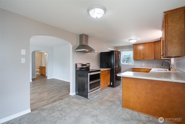 5030 S Park Ave S, Tacoma, WA 98408 - kitchen featuring wall chimney range hood, double oven range, freestanding refrigerator, brown cabinetry, and light countertops