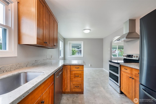 5030 S Park Ave S, Tacoma, WA 98408 - kitchen featuring appliances with stainless steel finishes, wall chimney exhaust hood, brown cabinetry, and light stone counters