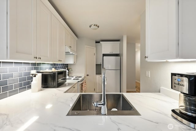 3806 Wetmore Ave, Everett, WA 98201 - kitchen with freestanding refrigerator, under cabinet range hood, white cabinets, backsplash, and light stone countertops