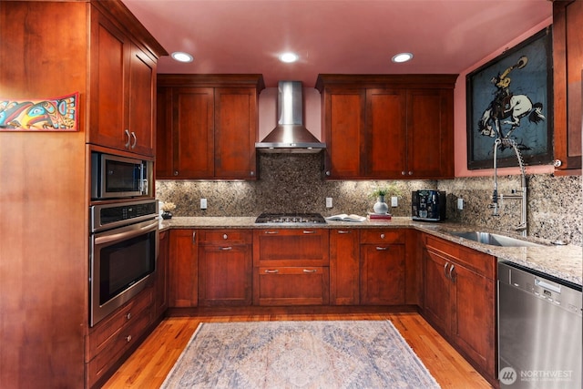 503 12th Ave E, Seattle, WA 98102 - kitchen featuring stainless steel appliances, wall chimney range hood, light wood-type flooring, light stone counters, and recessed lighting