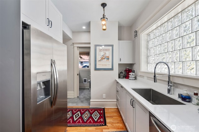 503 12th Ave E, Seattle, WA 98102 - kitchen featuring stainless steel appliances, light countertops, white cabinets, decorative light fixtures, and light wood-style floors