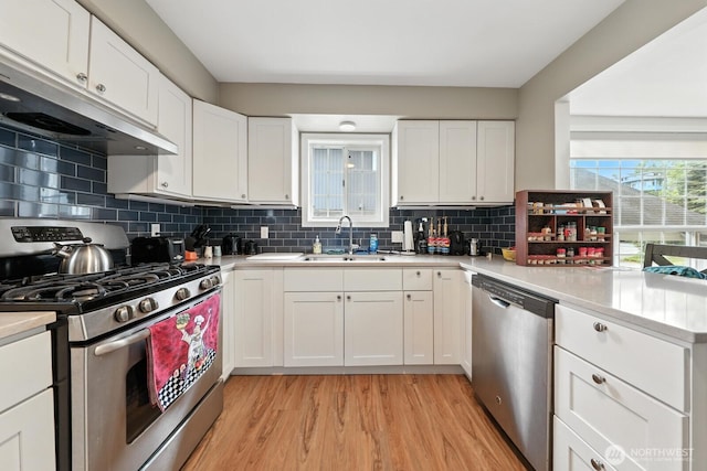 3827 Wetmore Ave, Everett, WA 98201 - kitchen featuring stainless steel appliances, light wood finished floors, exhaust hood, light countertops, and white cabinetry