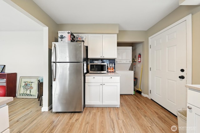 3827 Wetmore Ave, Everett, WA 98201 - kitchen featuring stainless steel appliances, stacked washing machine and dryer, white cabinets, light wood finished floors, and light countertops