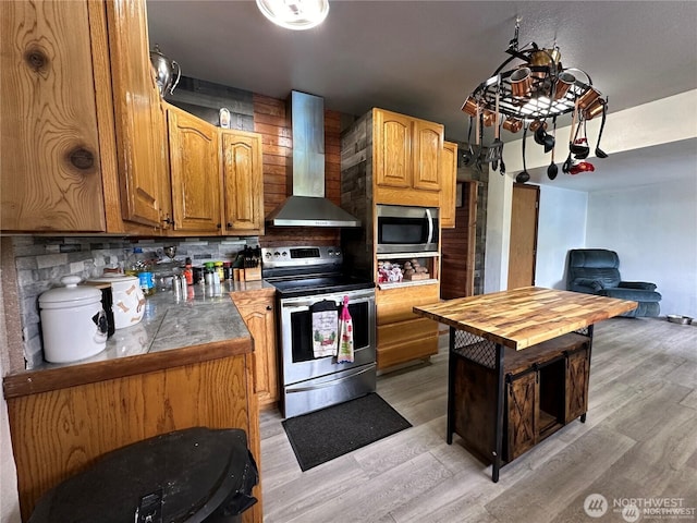 715 Copalis Beach Rd, Copalis Beach, WA 98535 - kitchen featuring appliances with stainless steel finishes, wall chimney range hood, light wood-style flooring, tasteful backsplash, and wooden counters