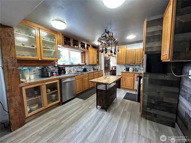 715 Copalis Beach Rd, Copalis Beach, WA 98535 - kitchen with stainless steel dishwasher, wood counters, light wood finished floors, decorative backsplash, and glass insert cabinets