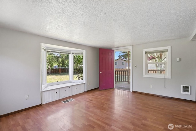1425 N 1st Ave, Kelso, WA 98626 - unfurnished room with wood finished floors, a textured ceiling, and heating unit