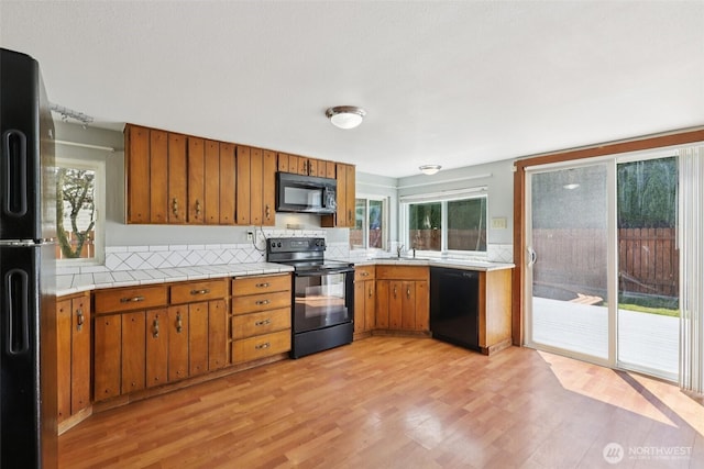 1425 N 1st Ave, Kelso, WA 98626 - kitchen featuring black appliances, brown cabinets, light wood-style flooring, and tile counters