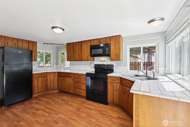 1425 N 1st Ave, Kelso, WA 98626 - kitchen featuring black appliances, brown cabinets, light wood finished floors, tasteful backsplash, and tile countertops