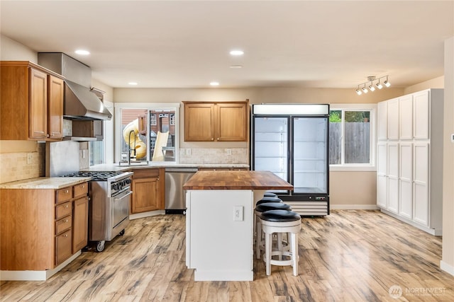 932 Tipsoo Loop N, Rainier, WA 98576 - kitchen featuring extractor fan, appliances with stainless steel finishes, butcher block counters, light wood-style flooring, and a kitchen breakfast bar