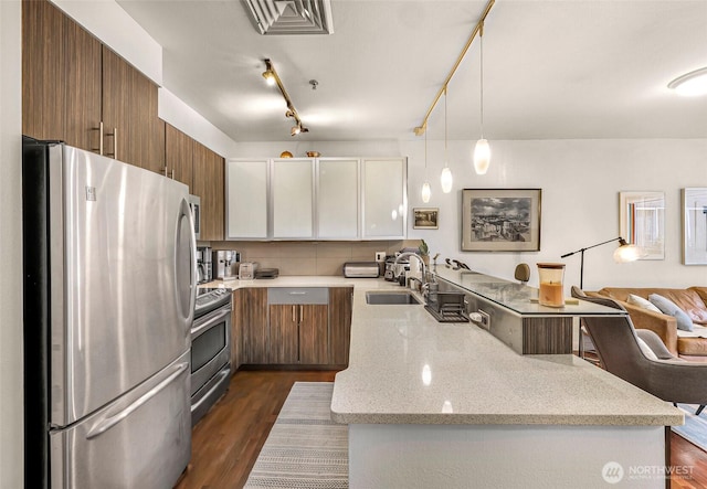 3104 Western Ave Unit 610, Seattle, WA 98121 - kitchen featuring stainless steel appliances, a peninsula, brown cabinetry, light stone countertops, and hanging light fixtures