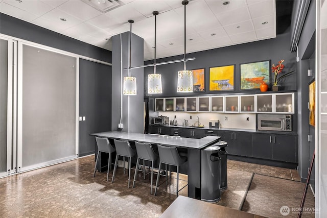 3104 Western Ave Unit 610, Seattle, WA 98121 - bar featuring stainless steel microwave, a paneled ceiling, and hanging light fixtures