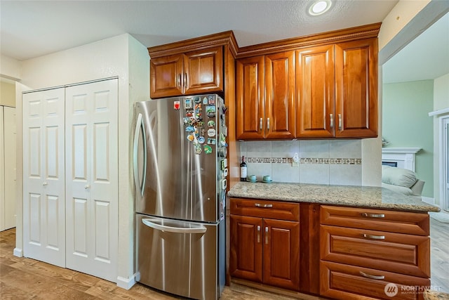4164 Factoria Blvd SE Unit B11, Bellevue, WA 98006 - kitchen featuring freestanding refrigerator, tasteful backsplash, light stone countertops, and brown cabinetry