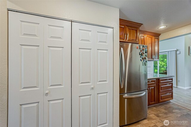4164 Factoria Blvd SE Unit B11, Bellevue, WA 98006 - kitchen with freestanding refrigerator, light wood-style floors, brown cabinets, and light stone countertops