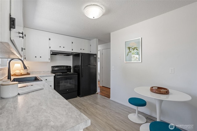 3317 N Baltimore St, Tacoma, WA 98407 - kitchen with black appliances, light wood-style flooring, light countertops, under cabinet range hood, and white cabinets