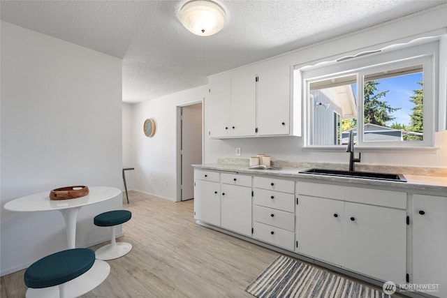 3317 N Baltimore St, Tacoma, WA 98407 - kitchen with white cabinetry, a textured ceiling, light wood finished floors, and light countertops