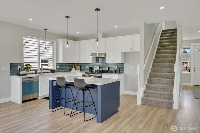 6410 S Fife St, Tacoma, WA 98409 - kitchen featuring dishwashing machine, stainless steel range with electric stovetop, under cabinet range hood, a kitchen island, and decorative backsplash