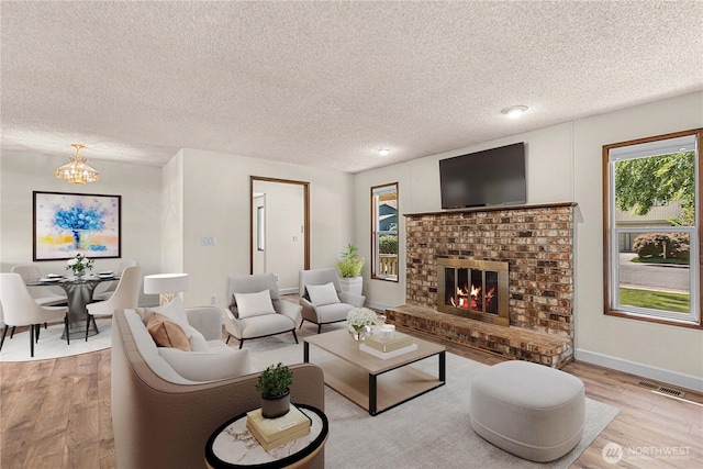 1201 Poe St, Wenatchee, WA 98801 - living room featuring wood finished floors, a textured ceiling, a chandelier, and a fireplace