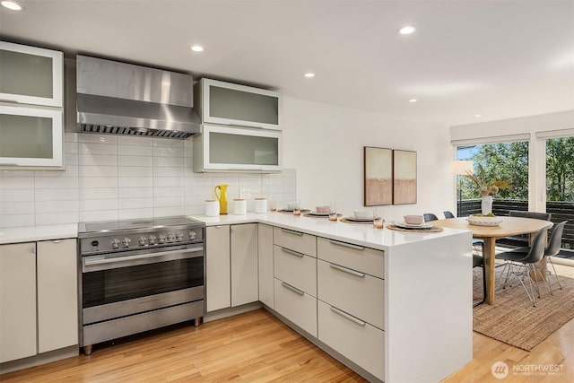 2434 64th Ave SE, Mercer Island, WA 98040 - kitchen with high end stove, wall chimney range hood, a peninsula, light countertops, and backsplash