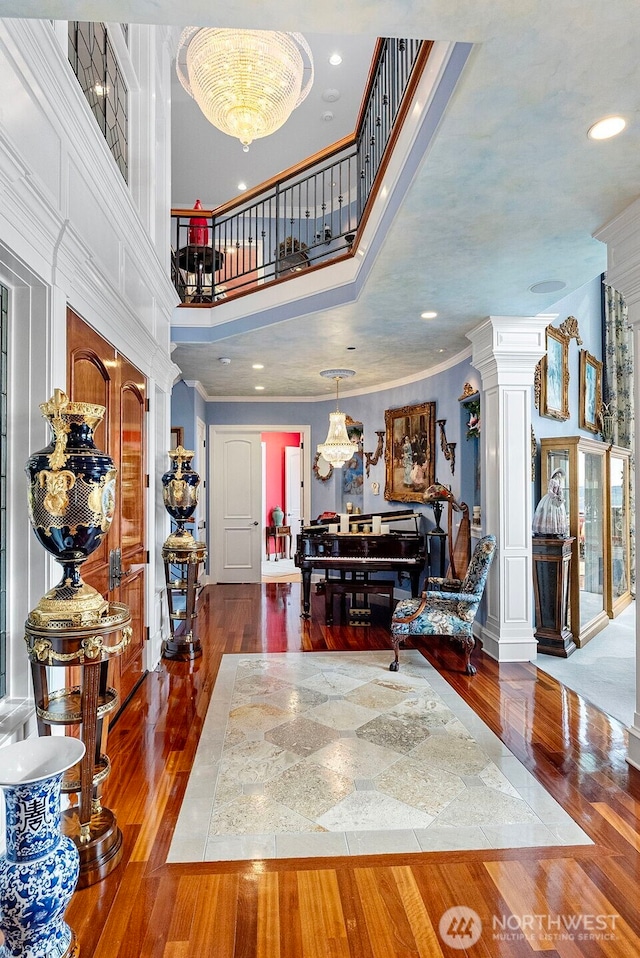 1022 7th Ct, Fox Island, WA 98333 - entryway with hardwood / wood-style floors, a chandelier, decorative columns, a high ceiling, and ornamental molding