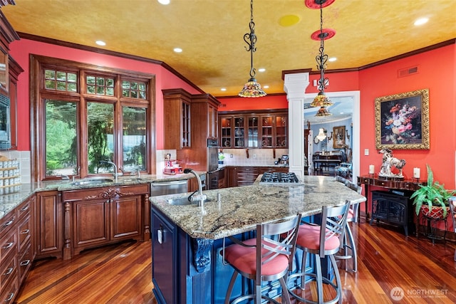 1022 7th Ct, Fox Island, WA 98333 - kitchen with dark wood-type flooring, light stone countertops, glass insert cabinets, tasteful backsplash, and ornamental molding