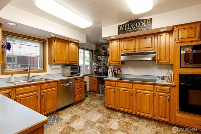 1130 Central Dr, Coulee Dam, WA 99116 - kitchen with black appliances, under cabinet range hood, brown cabinets, light stone finish floors, and light countertops