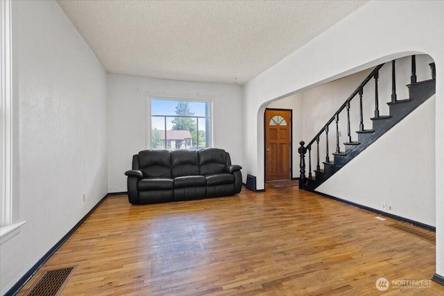 524 E 9th Ave, Spokane, WA 99202 - living room featuring arched walkways, wood finished floors, a textured ceiling, and stairway