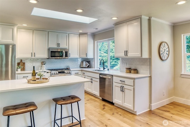 4957 Lewis Ave, Bellingham, WA 98229 - kitchen featuring appliances with stainless steel finishes, a skylight, ornamental molding, a kitchen breakfast bar, and plenty of natural light