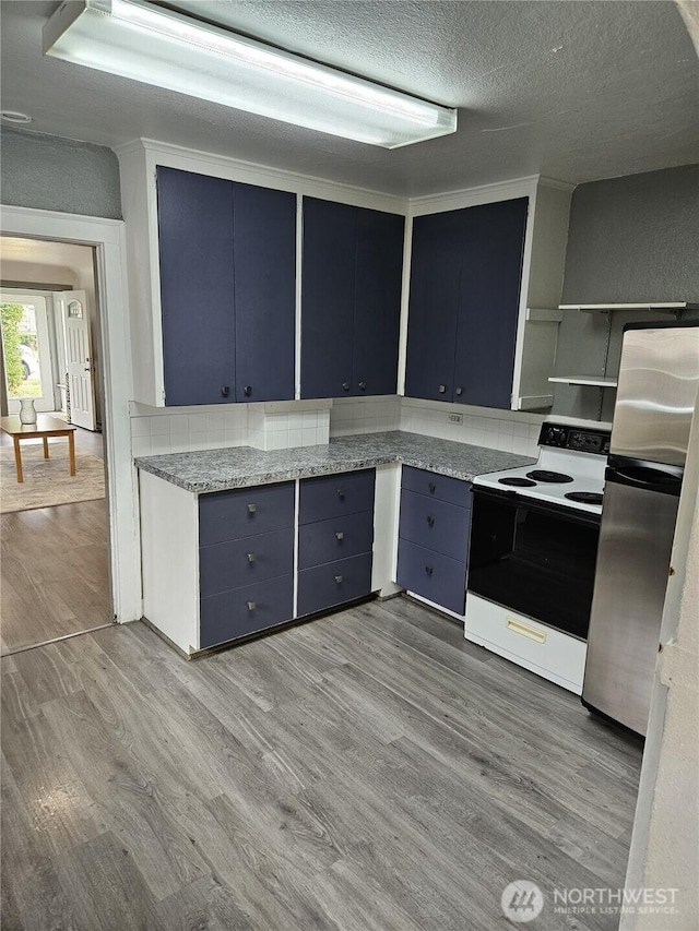 3023 Aberdeen Ave, Hoquiam, WA 98550 - kitchen featuring white electric stove, blue cabinetry, wood finished floors, freestanding refrigerator, and a textured ceiling