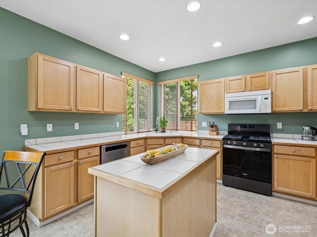 12732 69th Dr SE, Snohomish, WA 98296 - kitchen with stainless steel appliances, tile counters, light brown cabinets, recessed lighting, and a center island