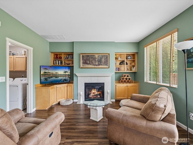 12732 69th Dr SE, Snohomish, WA 98296 - living room with washing machine and dryer, dark wood-style flooring, a tiled fireplace, and built in shelves