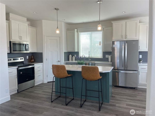 986 N Rock Rose Ave, Sequim, WA 98382 - kitchen with appliances with stainless steel finishes, decorative backsplash, a center island, a kitchen bar, and light countertops