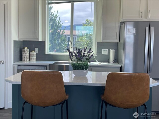 986 N Rock Rose Ave, Sequim, WA 98382 - kitchen with tasteful backsplash, white cabinets, freestanding refrigerator, and light stone countertops