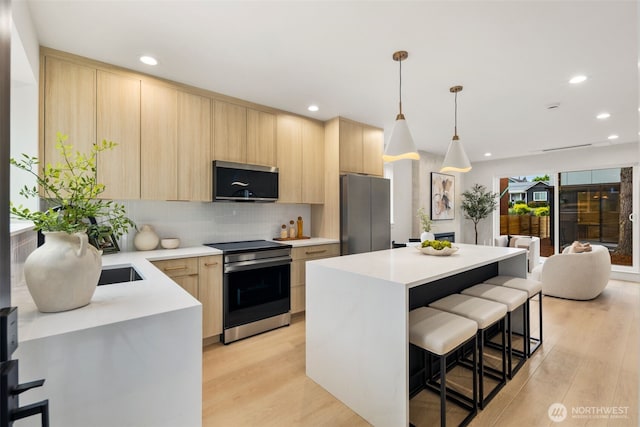 4525 S Orcas St, Seattle, WA 98118 - kitchen with stainless steel appliances, light brown cabinetry, light countertops, modern cabinets, and a kitchen breakfast bar