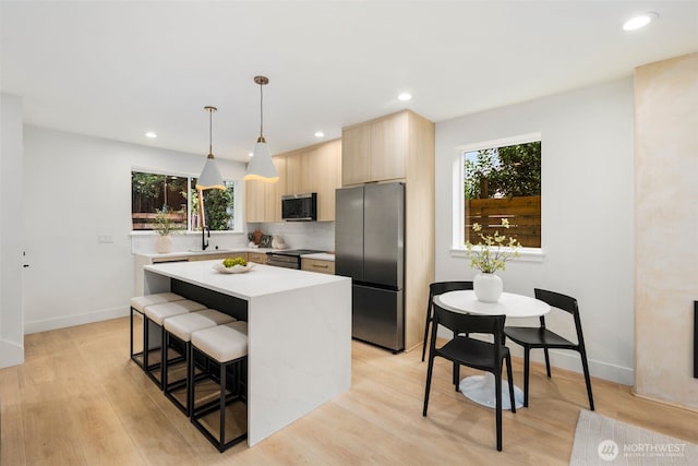 4525 S Orcas St, Seattle, WA 98118 - kitchen featuring appliances with stainless steel finishes, light brown cabinetry, light countertops, a center island, and a breakfast bar area