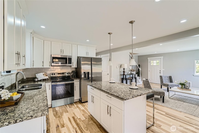 625 SW 122nd St, Seattle, WA 98146 - kitchen featuring stainless steel appliances, light wood-style flooring, white cabinetry, a kitchen breakfast bar, and recessed lighting