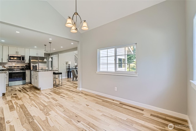 625 SW 122nd St, Seattle, WA 98146 - kitchen with stainless steel appliances, a kitchen breakfast bar, dark countertops, tasteful backsplash, and light wood-style flooring