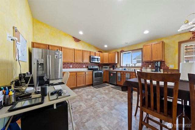925 S 11th Ave, Othello, WA 99344 - kitchen with stainless steel appliances, lofted ceiling, decorative backsplash, light countertops, and brown cabinets