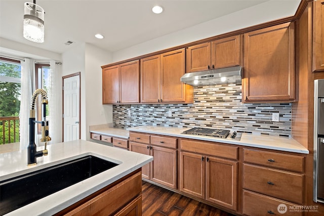 22820 41st Dr SE, Bothell, WA 98021 - kitchen with stainless steel gas stovetop, under cabinet range hood, brown cabinetry, light countertops, and dark wood-style floors