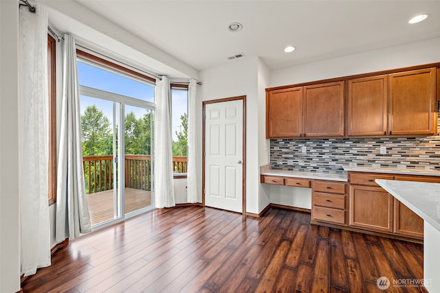 22820 41st Dr SE, Bothell, WA 98021 - kitchen featuring built in desk, light countertops, brown cabinetry, decorative backsplash, and dark wood-type flooring