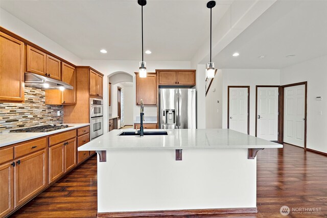 22820 41st Dr SE, Bothell, WA 98021 - kitchen featuring stainless steel appliances, under cabinet range hood, arched walkways, dark wood-style flooring, and tasteful backsplash