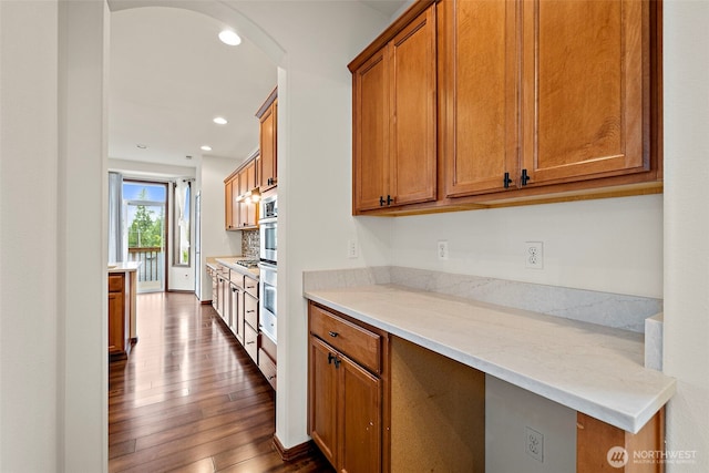 22820 41st Dr SE, Bothell, WA 98021 - kitchen with brown cabinets, dark wood finished floors, arched walkways, recessed lighting, and stainless steel oven