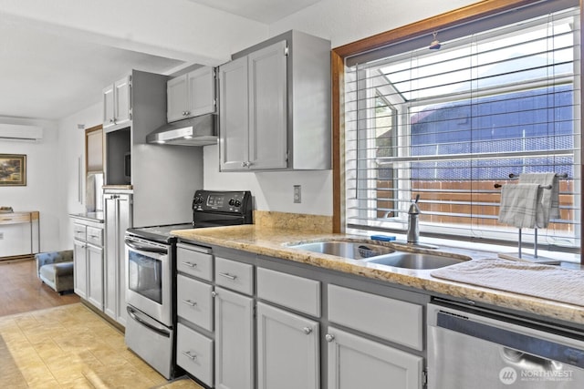 10208 D St E, Tacoma, WA 98445 - kitchen featuring appliances with stainless steel finishes, a wall mounted air conditioner, under cabinet range hood, and light stone counters