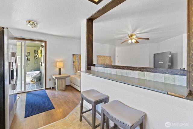 10208 D St E, Tacoma, WA 98445 - kitchen with stainless steel refrigerator with ice dispenser, a ceiling fan, a kitchen bar, and wood finished floors