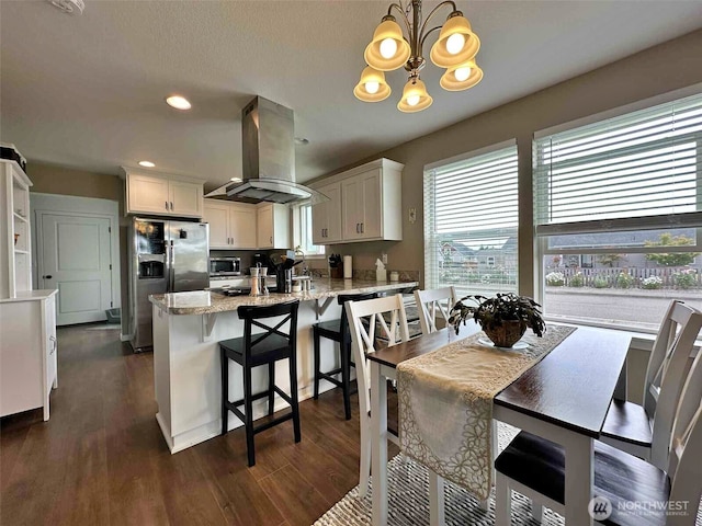 704 Roundtree Blvd, Winlock, WA 98596 - kitchen with island range hood, appliances with stainless steel finishes, a peninsula, white cabinets, and dark wood-style flooring