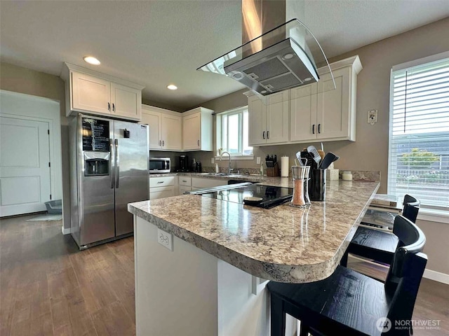 704 Roundtree Blvd, Winlock, WA 98596 - kitchen featuring stainless steel appliances, exhaust hood, a peninsula, white cabinets, and wood finished floors