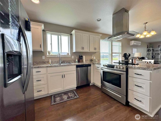 704 Roundtree Blvd, Winlock, WA 98596 - kitchen with stainless steel appliances, island range hood, a peninsula, dark wood-style flooring, and white cabinets