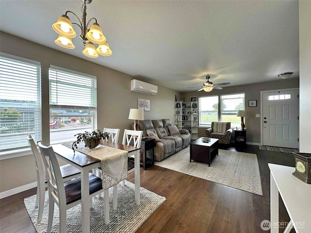 704 Roundtree Blvd, Winlock, WA 98596 - dining space with a wall unit AC, a ceiling fan, a chandelier, dark wood-style flooring, and a textured ceiling